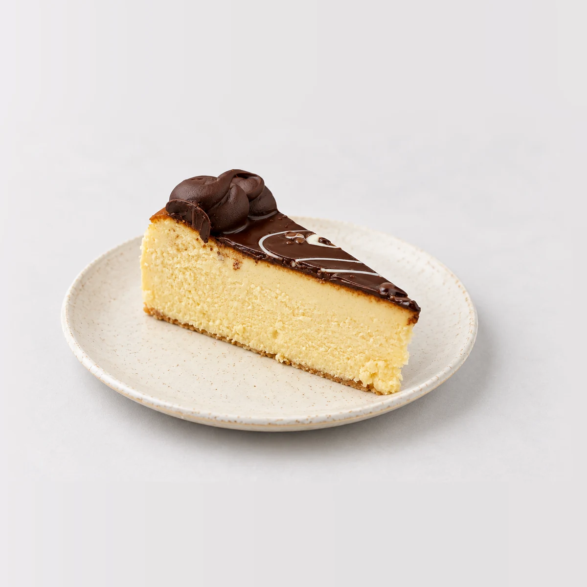 Slice of baked Bailey's cheesecake with a thin chocolate layer and a chocolate rosette on top.