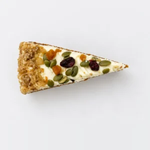 Carrot cake slice from above: cream cheese frosting with dried cranberries, apricot and pumpkin seeds.