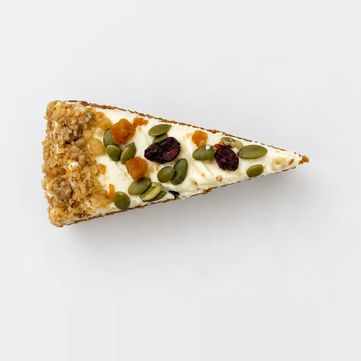 Carrot cake slice from above: cream cheese frosting with dried cranberries, apricot and pumpkin seeds.