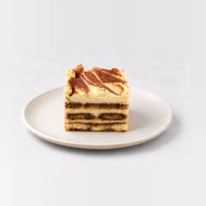 Side view of the tiramisu cake slice showing alternating layers of coffee-soaked sponge and cream.