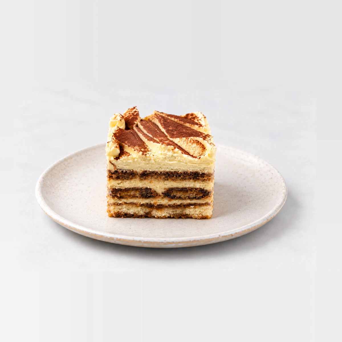 Side view of the tiramisu cake slice showing alternating layers of coffee-soaked sponge and cream.