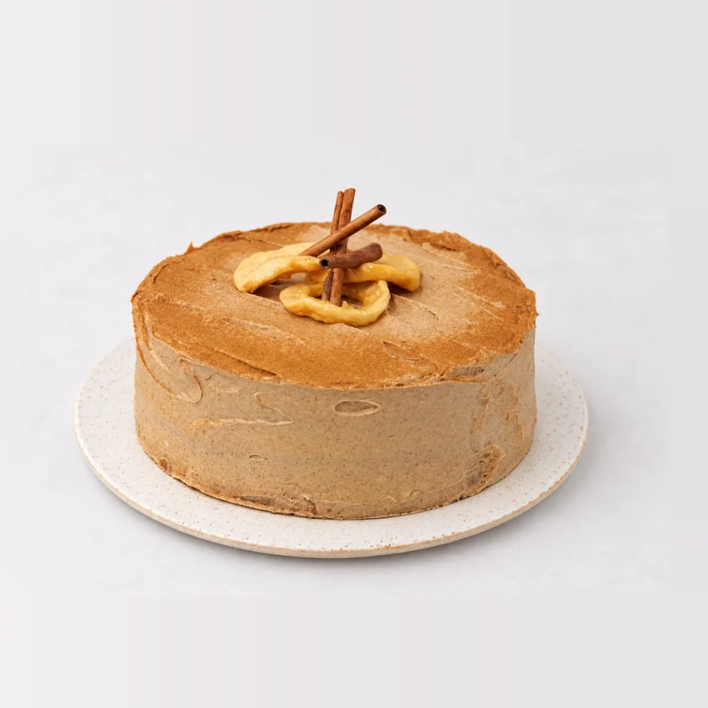 Apple and cinnamon tea cake covered in cinnamon frosting, topped with cinnamon sticks and apple slices.