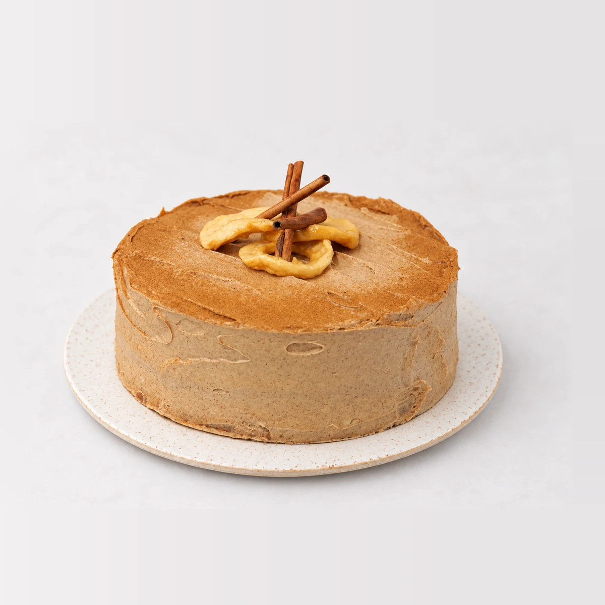 Apple and cinnamon tea cake covered in cinnamon frosting, topped with cinnamon sticks and apple slices.