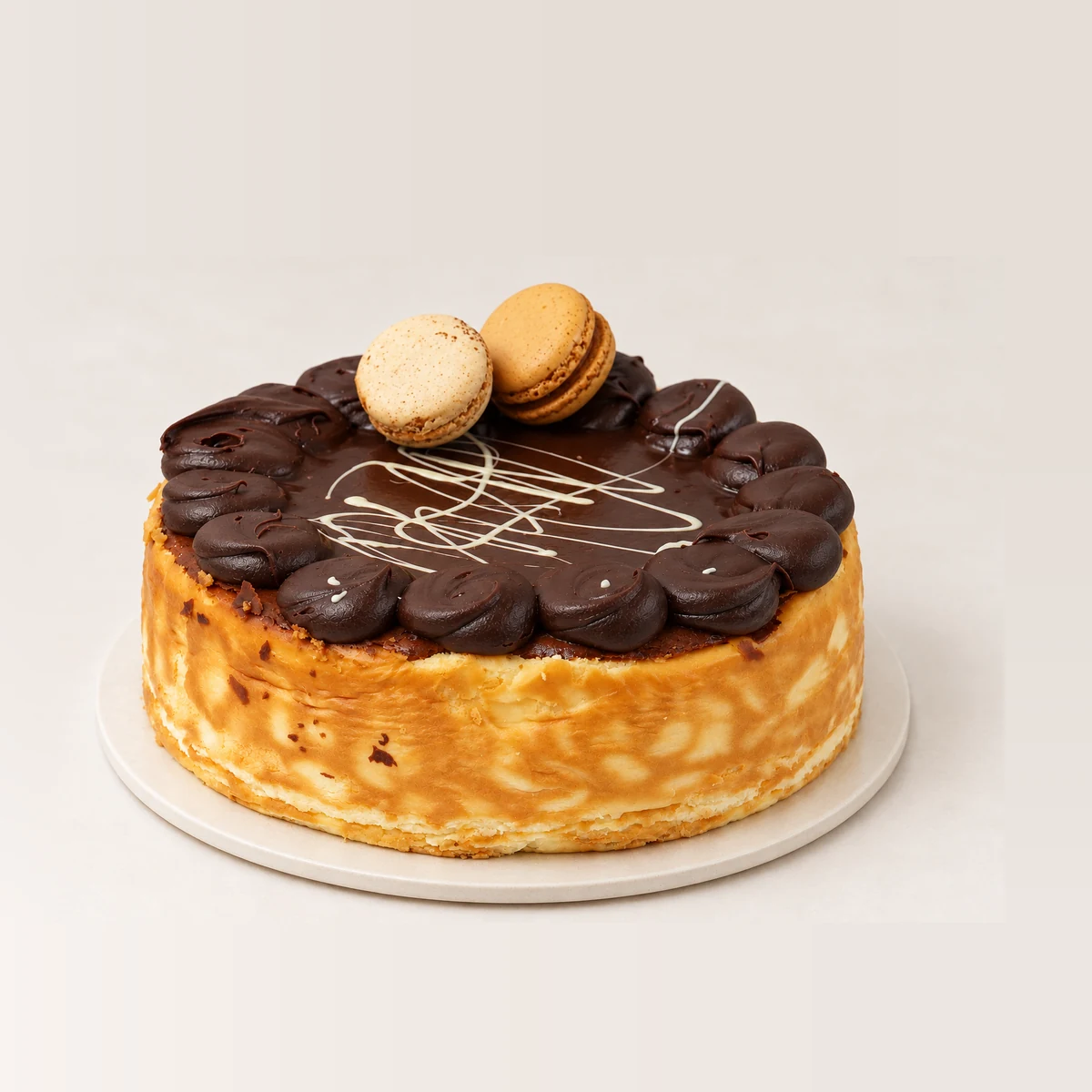 Close side view of the Bailey's cheesecake showing the golden cheesecake sides under the chocolate layer and macarons.