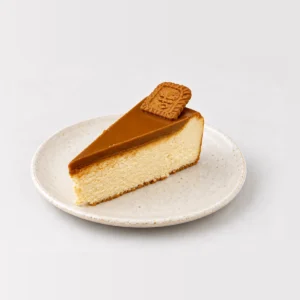 Slice of baked Biscoff cheesecake topped with Biscoff caramel and a Lotus biscuit.