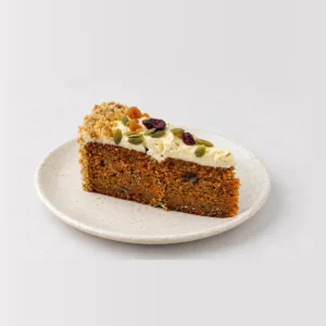 Slice of carrot cake showing spiced sponge, cream cheese frosting, dried fruit and seeds.