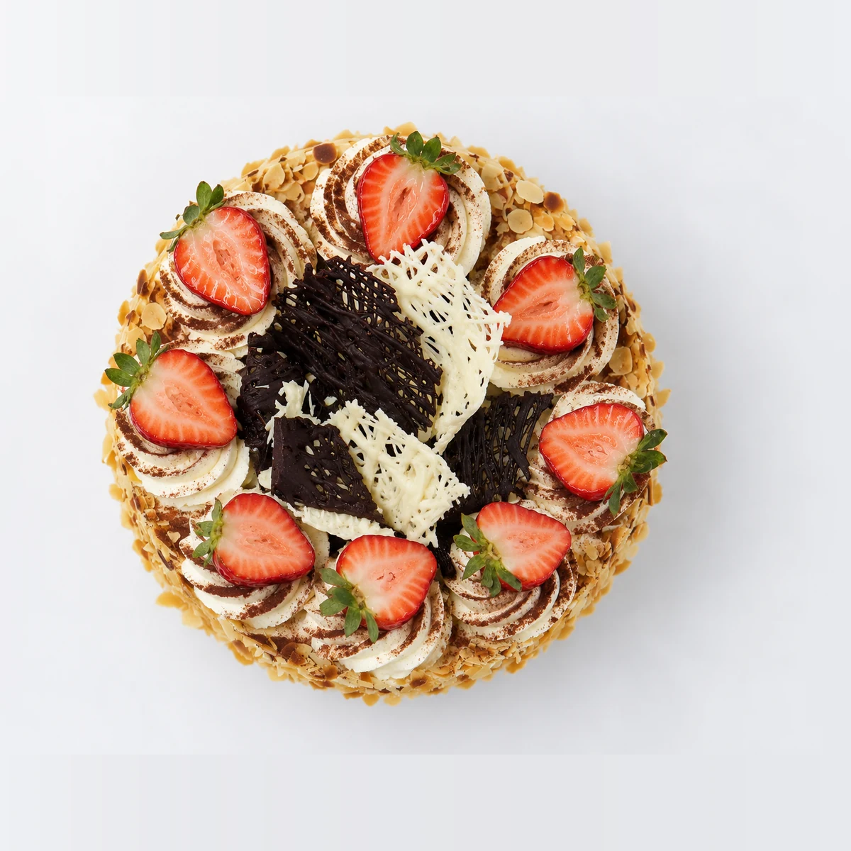 Continental cake from above: cream rosettes, halved strawberries and dark and white chocolate shards.