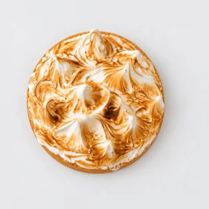 Lemon meringue tart from above: swirled meringue peaks caramelised to golden brown.