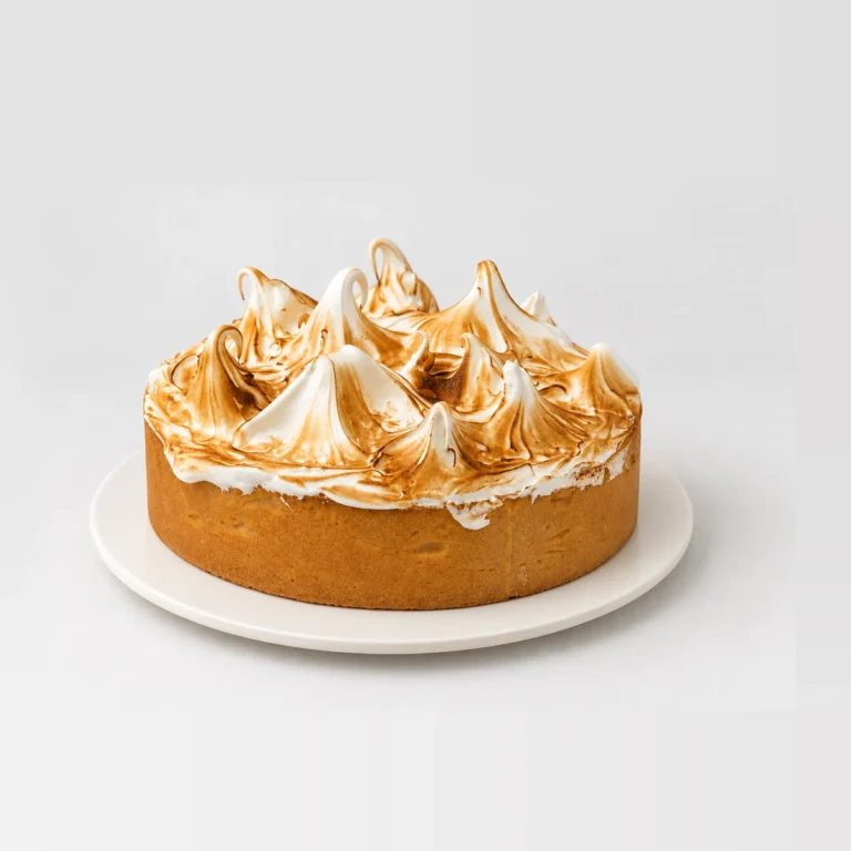 Lemon meringue tart topped with tall peaks of caramelised golden-brown meringue on a shortcrust base.