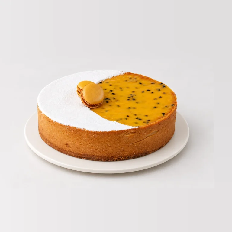 Passionfruit tart with half the top dusted with icing sugar and half covered in passionfruit curd, with two macarons.