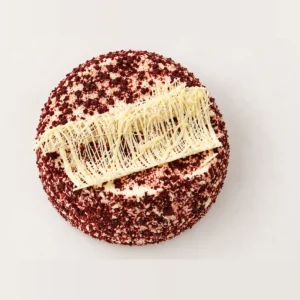 Red velvet cake from above: red velvet crumb around the edge and a white chocolate decoration across the top.
