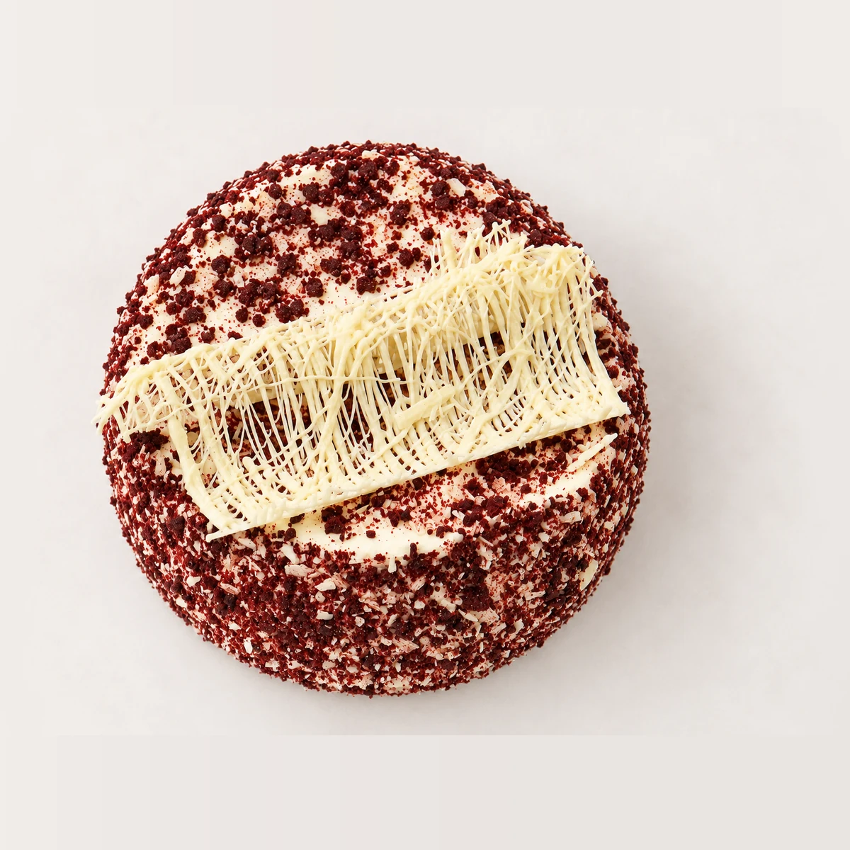Red velvet cake from above: red velvet crumb around the edge and a white chocolate decoration across the top.
