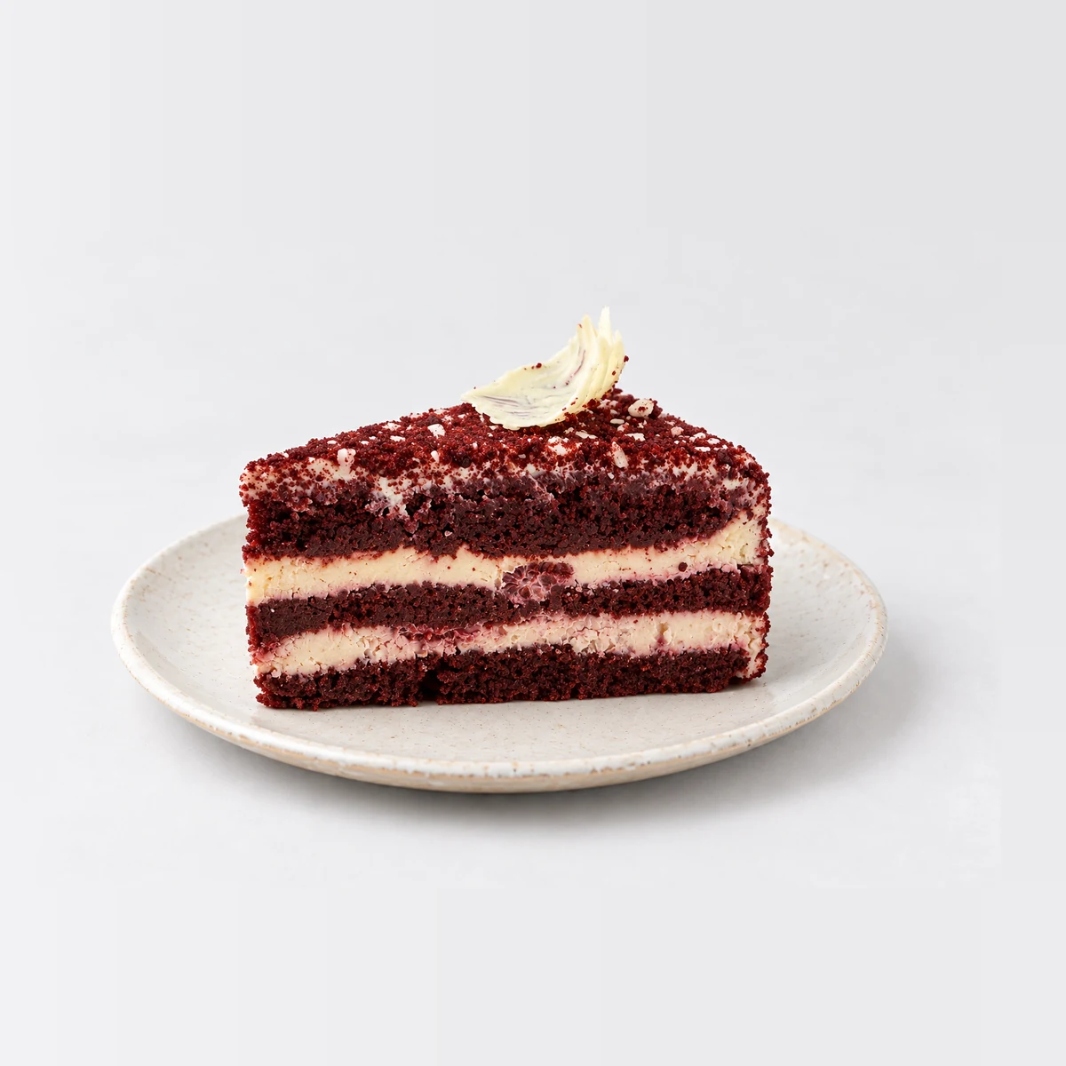 Side view of the red velvet slice showing red sponge and two layers of cream cheese filling.