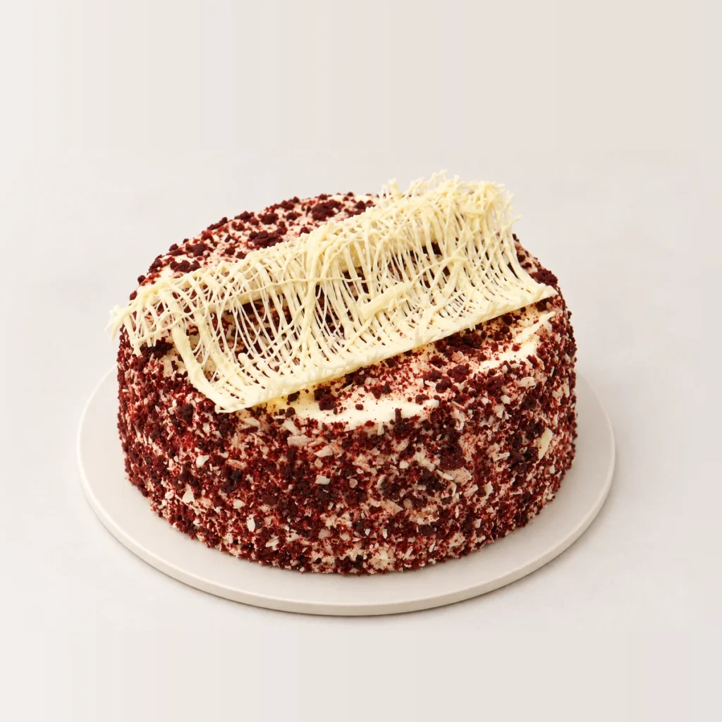 Close-up of the white chocolate decoration on the red velvet cake, with red velvet crumb around the sides.