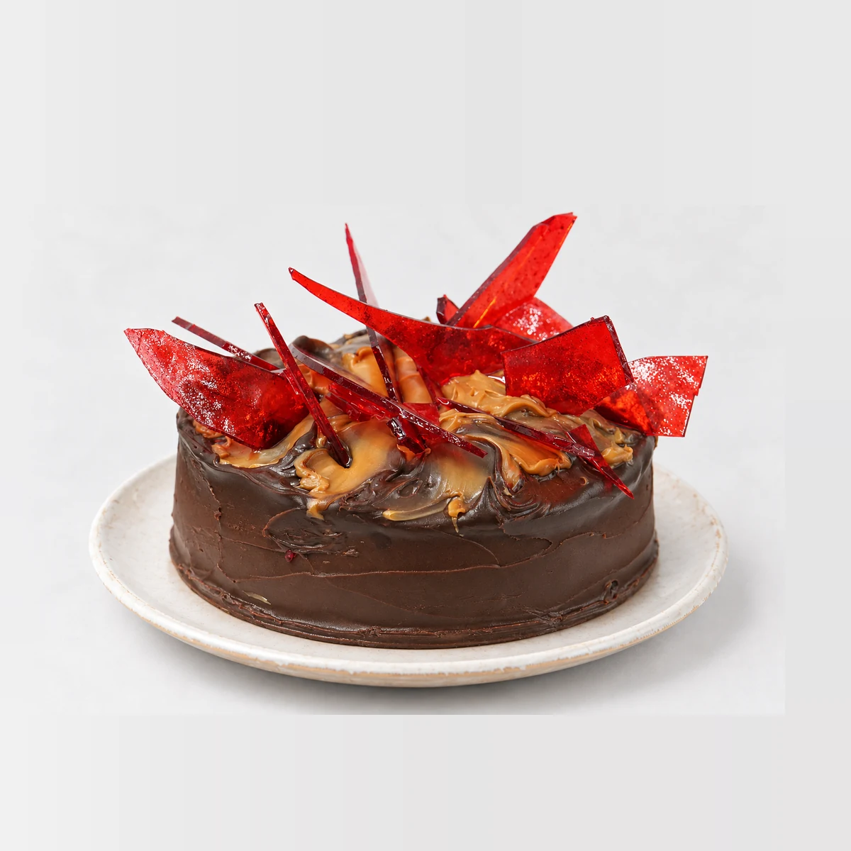 Side view of the Toffee Mars cake with its chocolate glaze and red toffee shards standing up from the top.