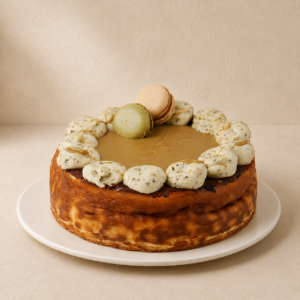 Baked pistachio cheesecake topped with pistachio cream rosettes and two macarons, on a white plate.