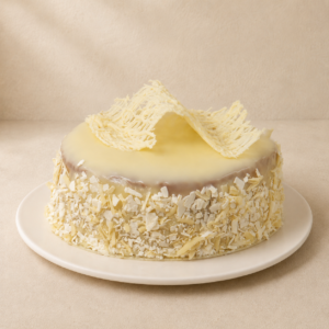 Arctic Mud Cake: a domed white chocolate mud cake with a glossy white glaze and white chocolate flakes.