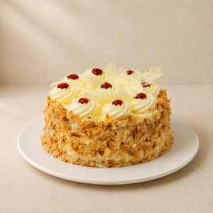 Jam sponge cake with flaked almond sides and cream rosettes finished with dots of red jam.