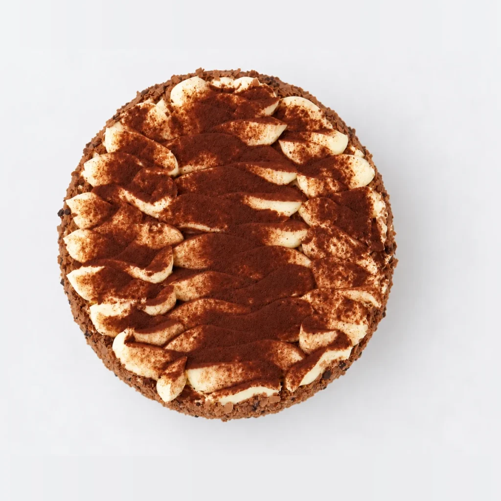 Tiramisu cake from above: swirls of cream dusted with cocoa powder.