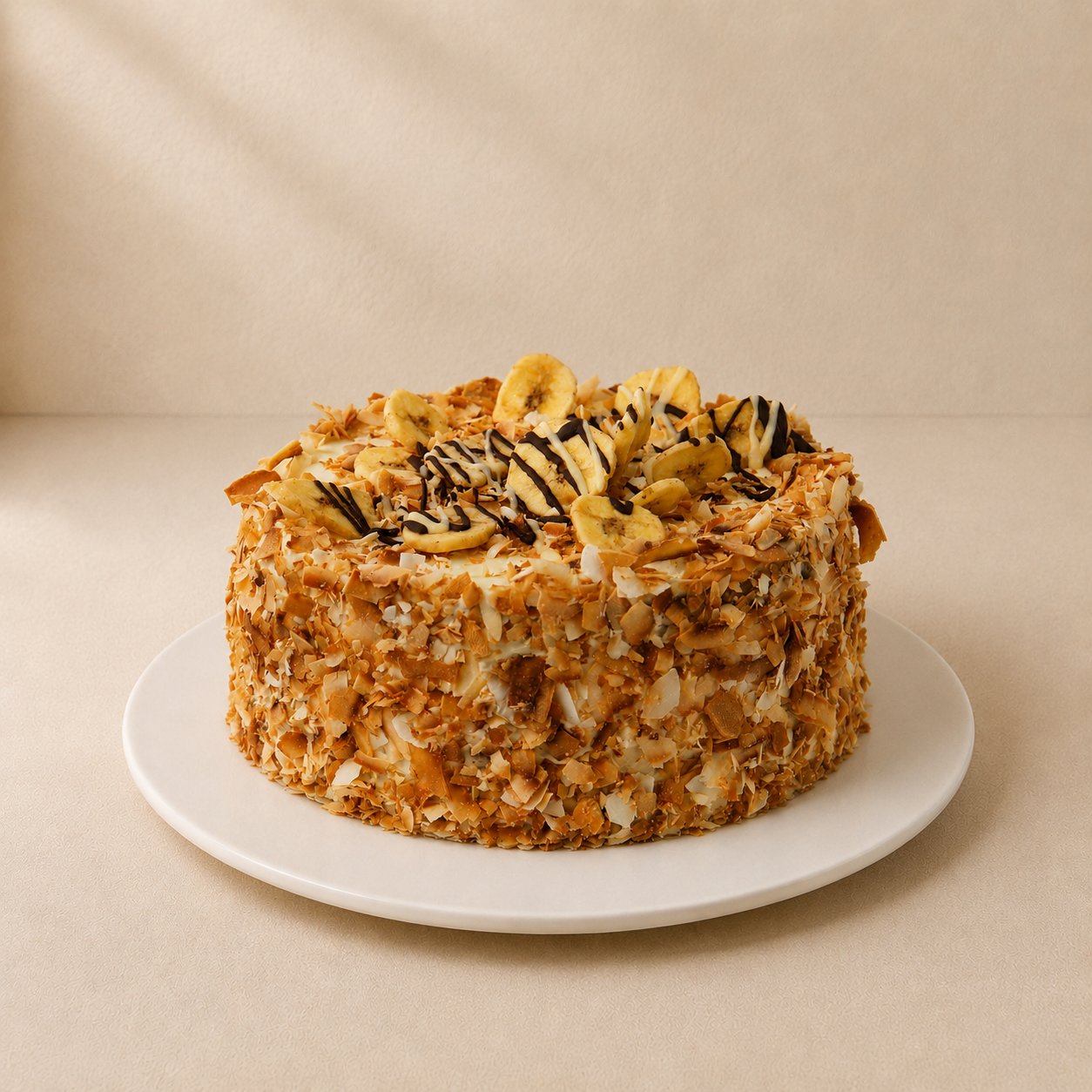 Tropical banana and coconut cake coated in toasted coconut and topped with banana and chocolate drizzle.