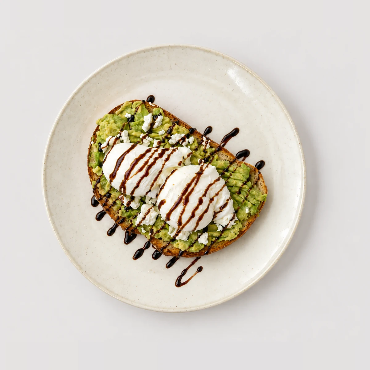 Avocado feta toast, poached eggs, dark drizzle — Top-down